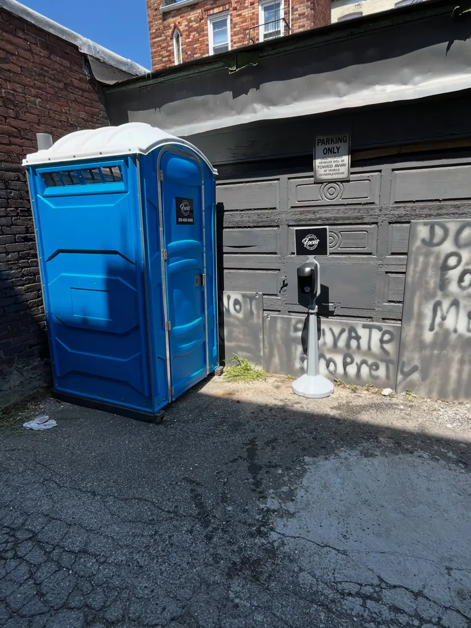 Standard porta potty beside a brick building