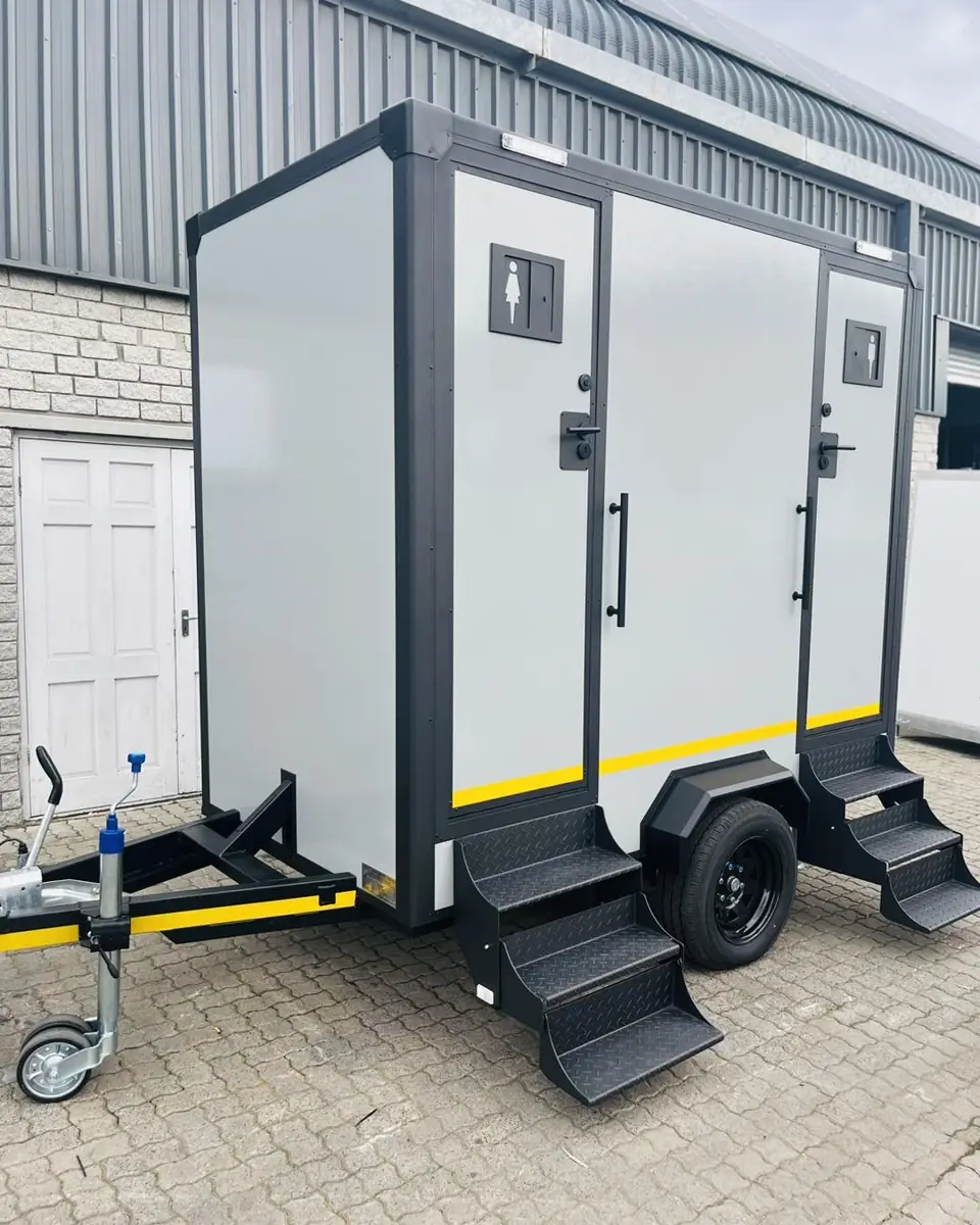 Two-stall portable restroom trailer with steps and handrails